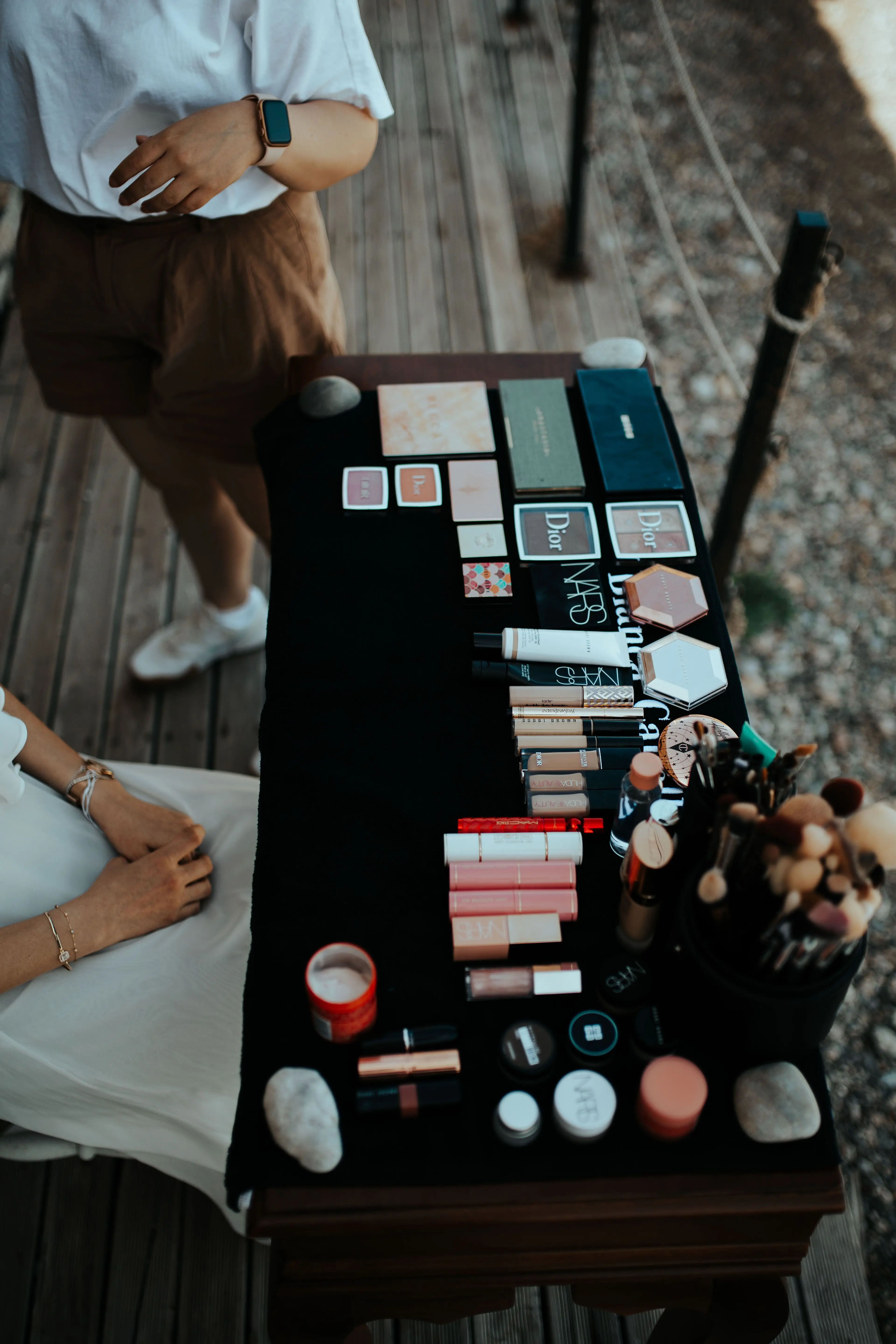 A makeup artist's branded kit laid out on a table outdoors, with no fixed location in sight