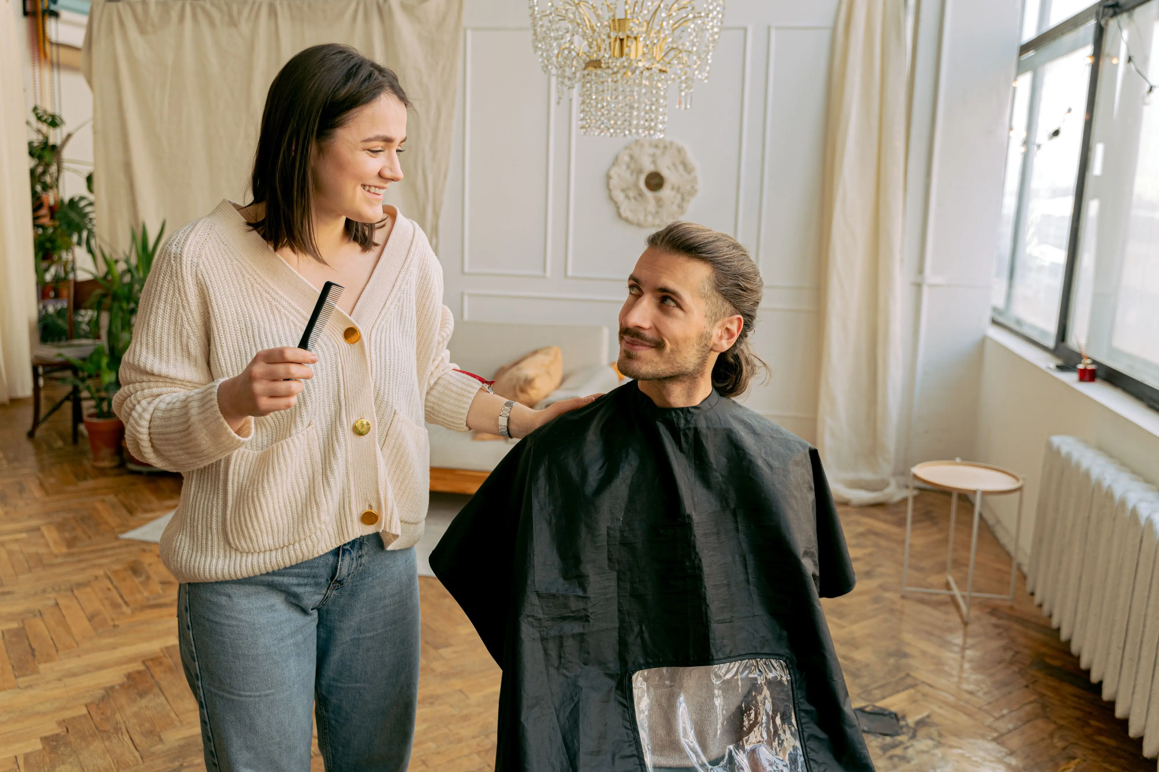 A hairstylist consulting warmly with a seated client during a haircut